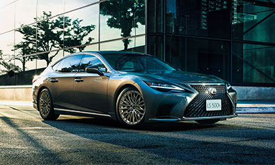A silver LS parked on a city street next to a glass building.