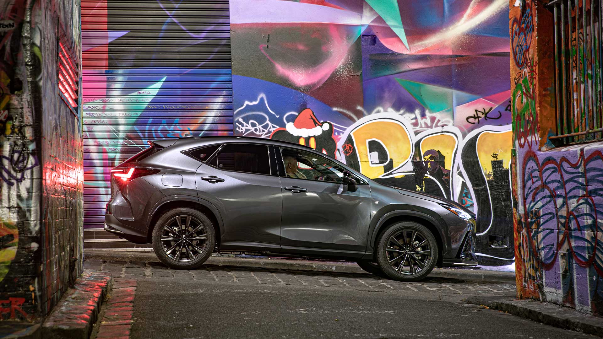 Grey Lexus hybrid SUV, the NX 450h+ shown in a graffiti street.