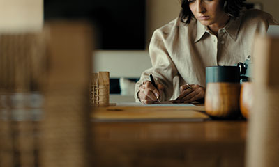 A woman writes on a wooden desk.