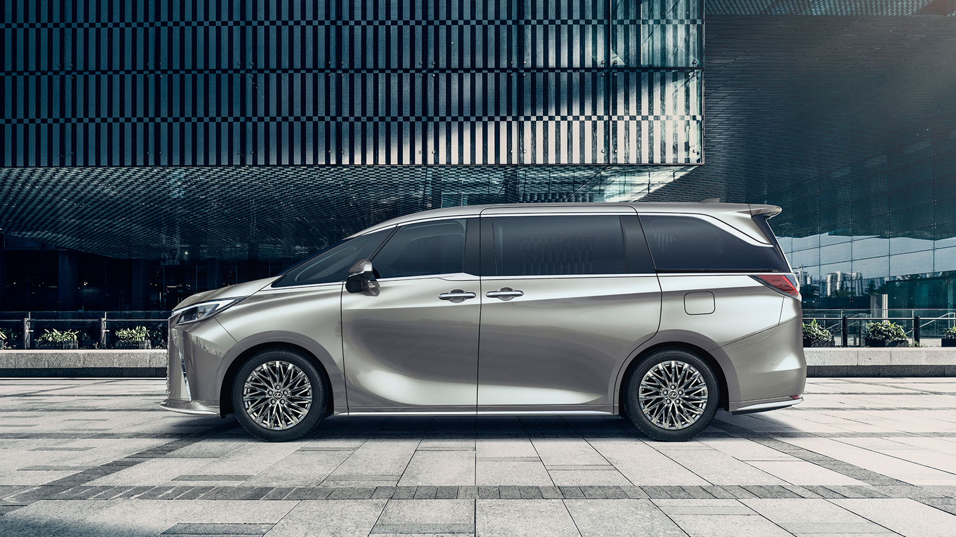 Side on view of a silver LM parked on a paved streetscape.