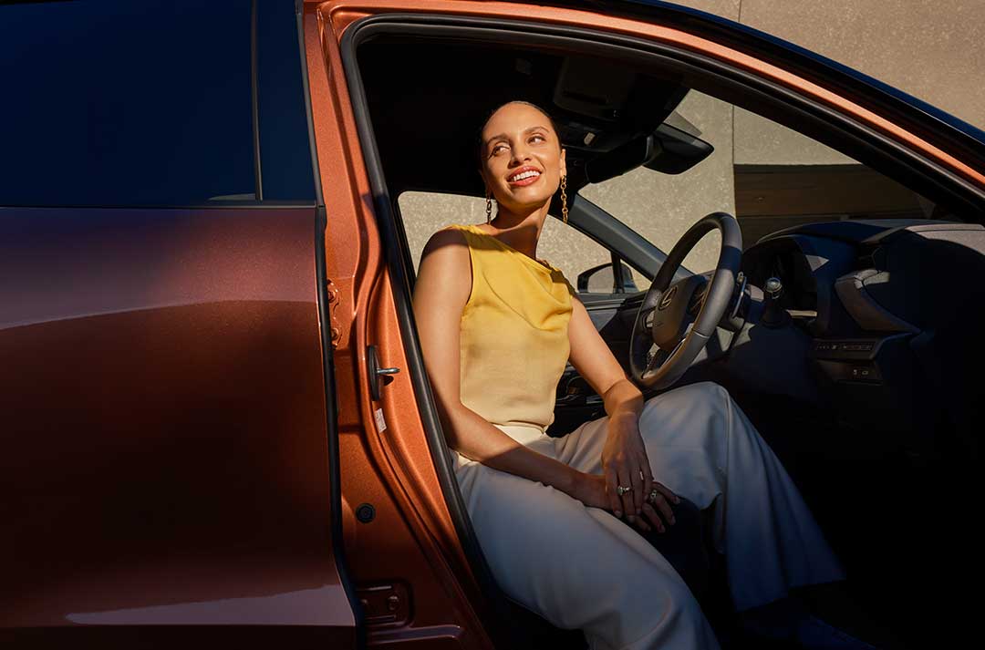 Woman sitting in the driver's seat with the car door open.