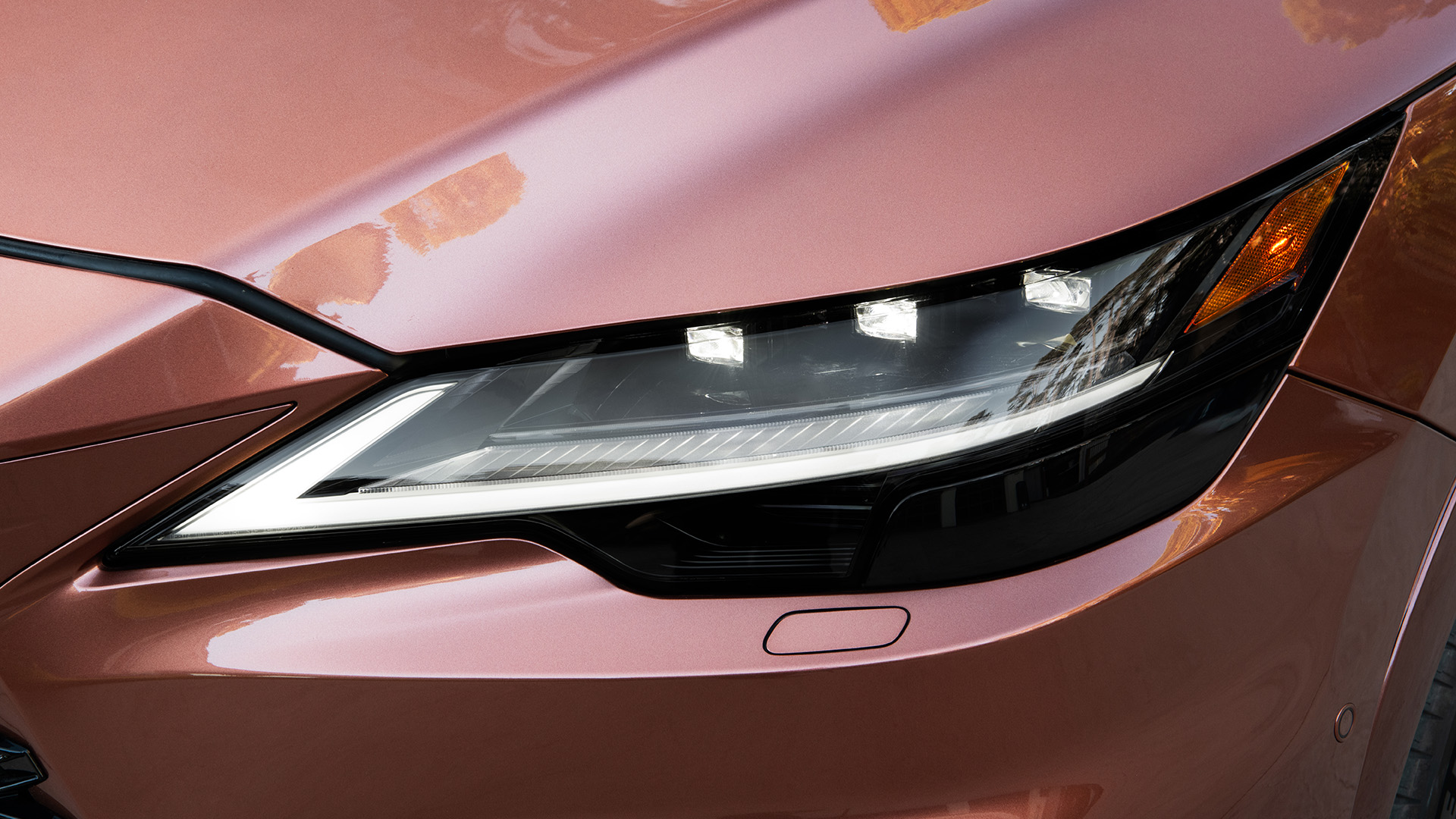 A close up on the headlight of a copper colored RX.